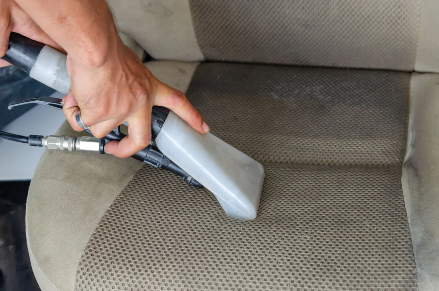 Fabric vehicle seat being cleaned with an extraction tool